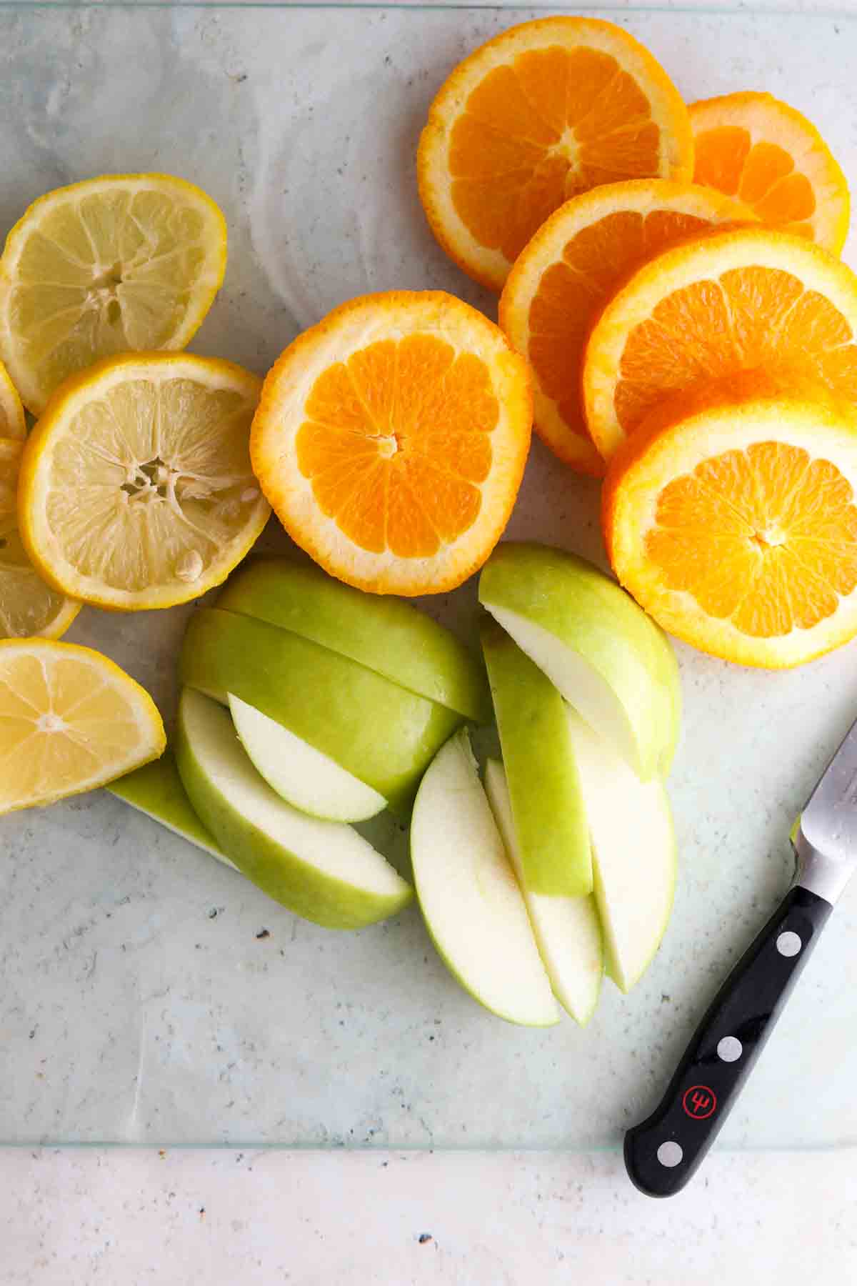 Apples, oranges and lemons on a cutting board. 