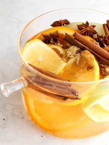 Lemons, apples, oranges, and cinnamon in a pot.