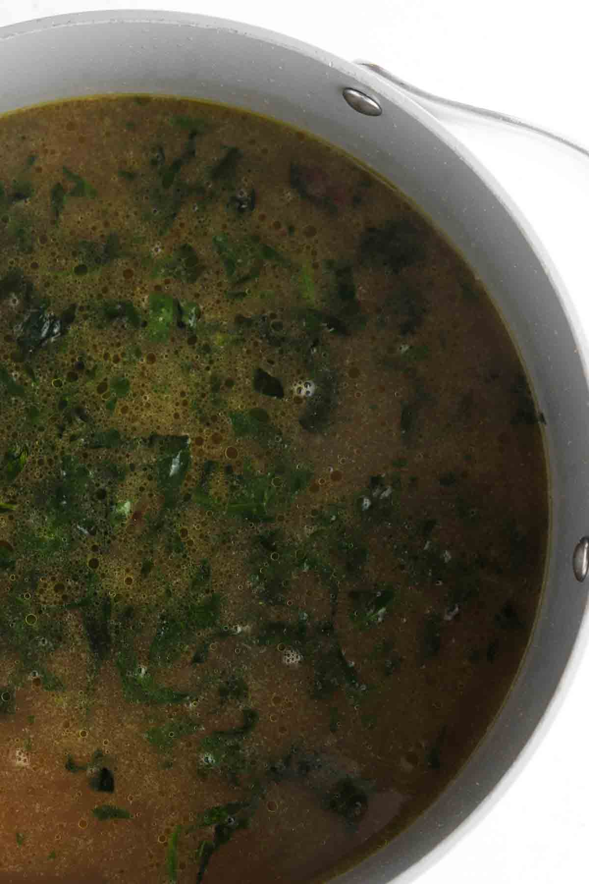Onions, chopped spinach, assorted spices, chopped carrots and bone broth in a large soup pot. 
