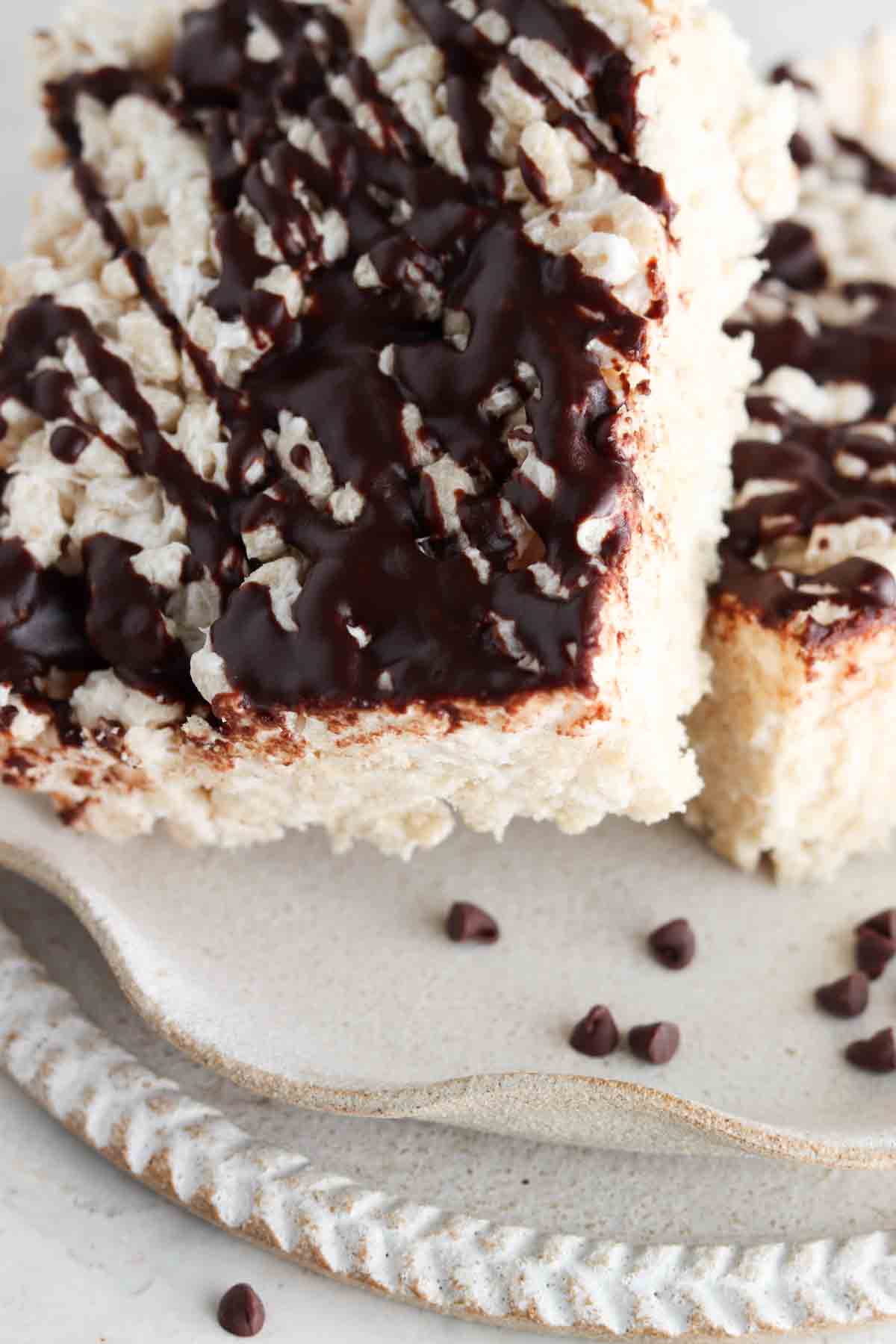 Two rice crispy treats on a plate stacked on top of each other with chocolate on top.