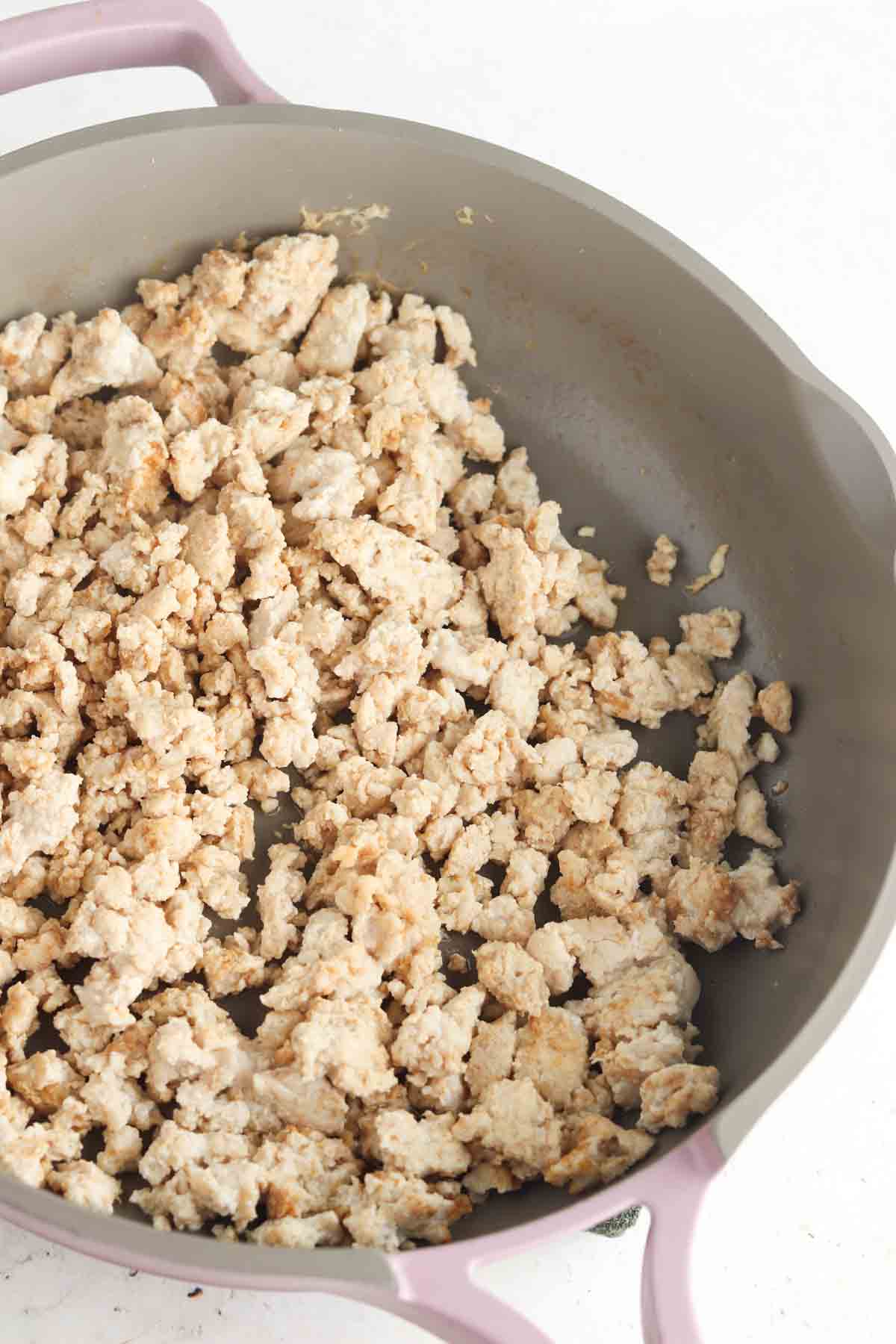 Ground chicken and spices in a frying pan.