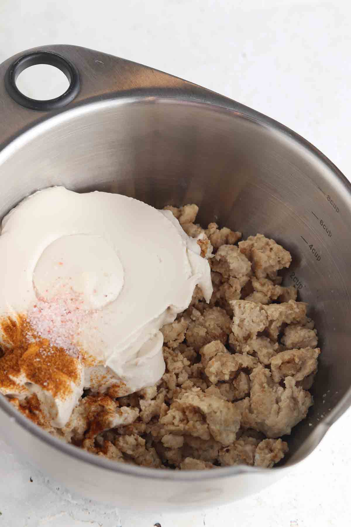 Cream cheese and spiced ground chicken in a large bowl. 