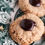 Thumbprint cookies on a green and white plate with chocolate ganache in the middle.