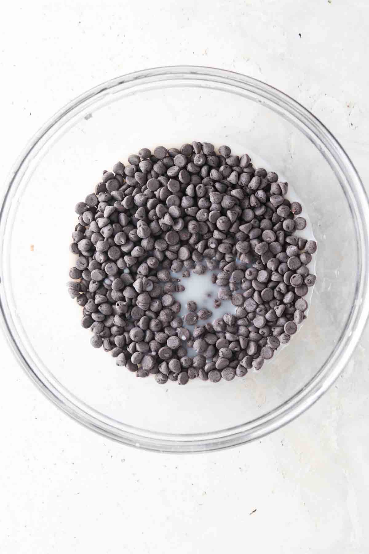 Chocolate chips and almond milk in a glass bowl. 