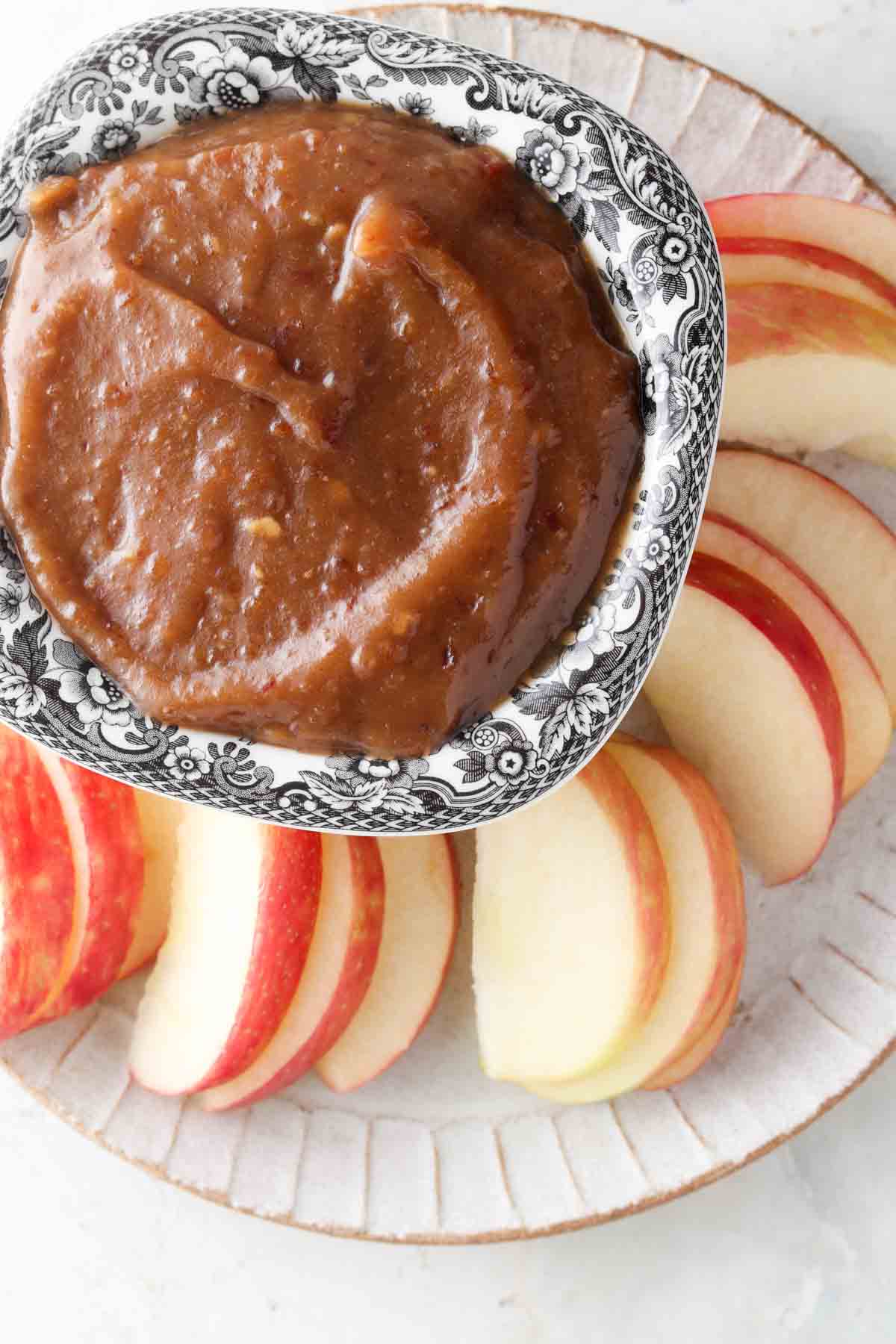 Fruit dip in a black and white bowl with apple slices on the side. 