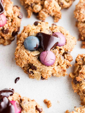 Chocolate chip cookies with candies on top laid out on wax paper.