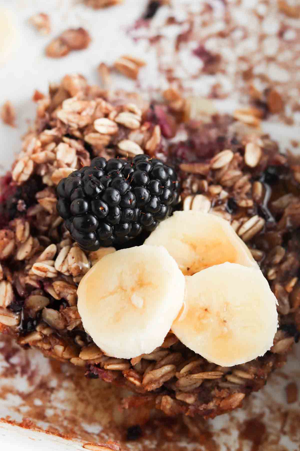 Oatmeal bake in a white casserole dish with blackberries and bananas on top.
