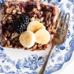 Blackberry baked oatmeal on a blue plate with banana slices and blackberries.