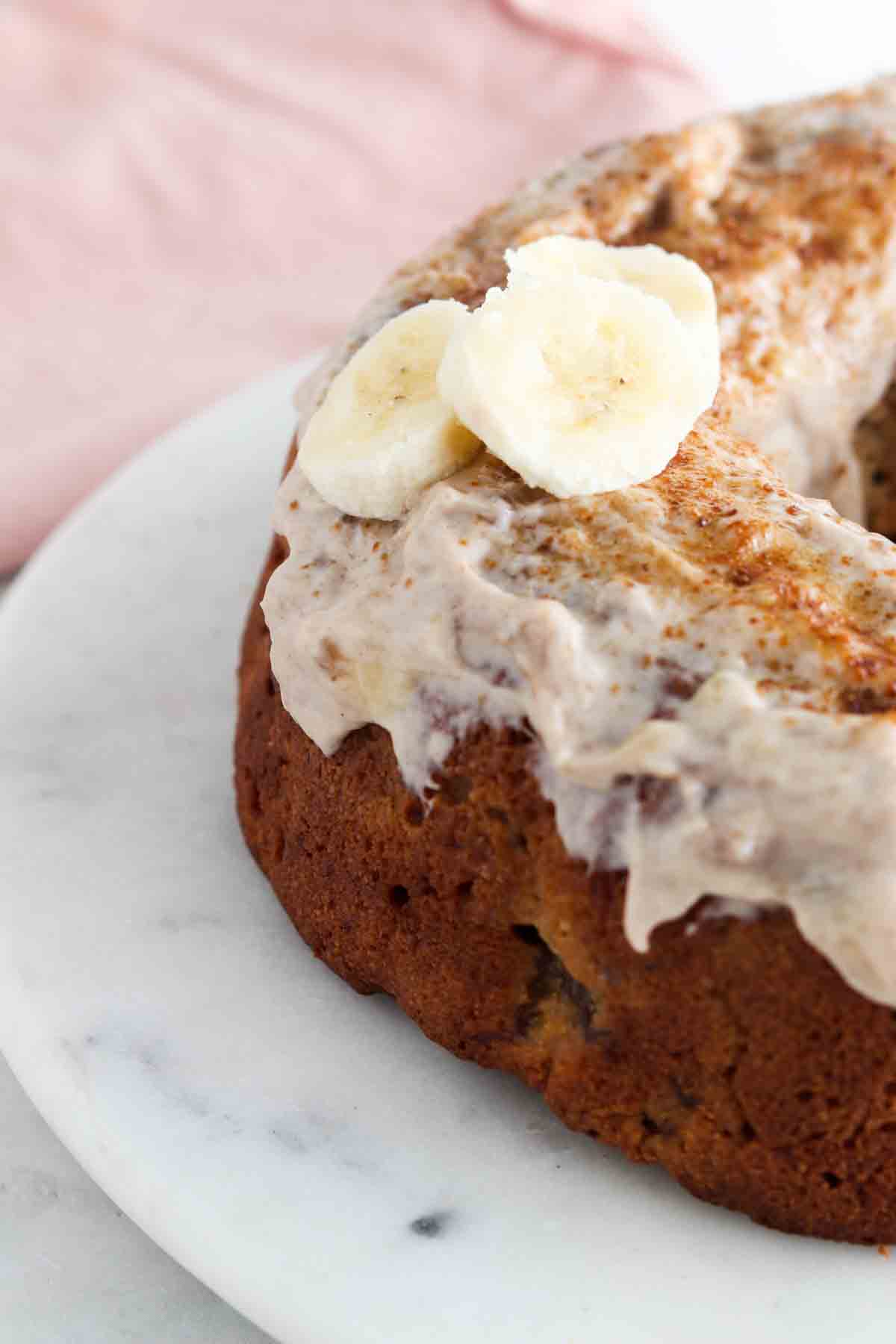 Banana cake on a cake stand with banana frosting on top. 