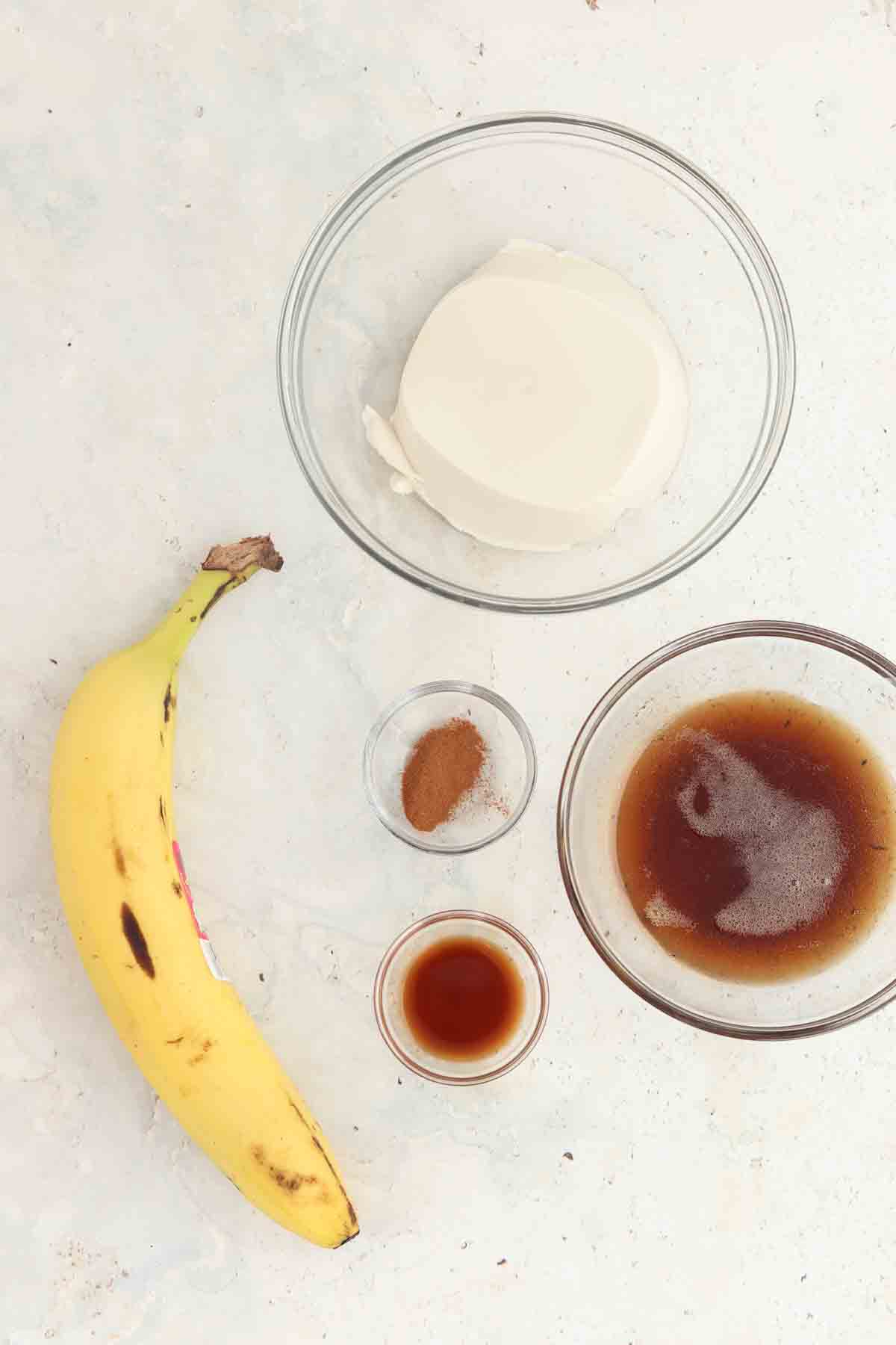 Banana maple frosting ingredients laid out in small glass bowls. 
