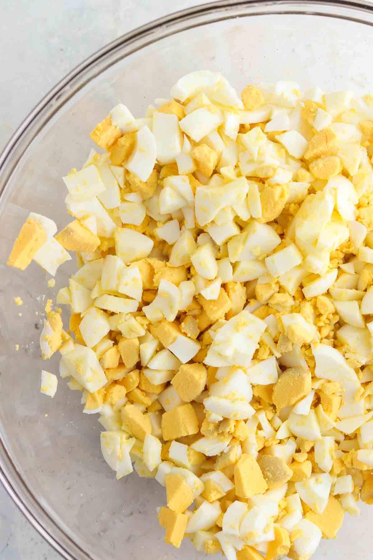 Chopped up hard boiled egg in a glass bowl.