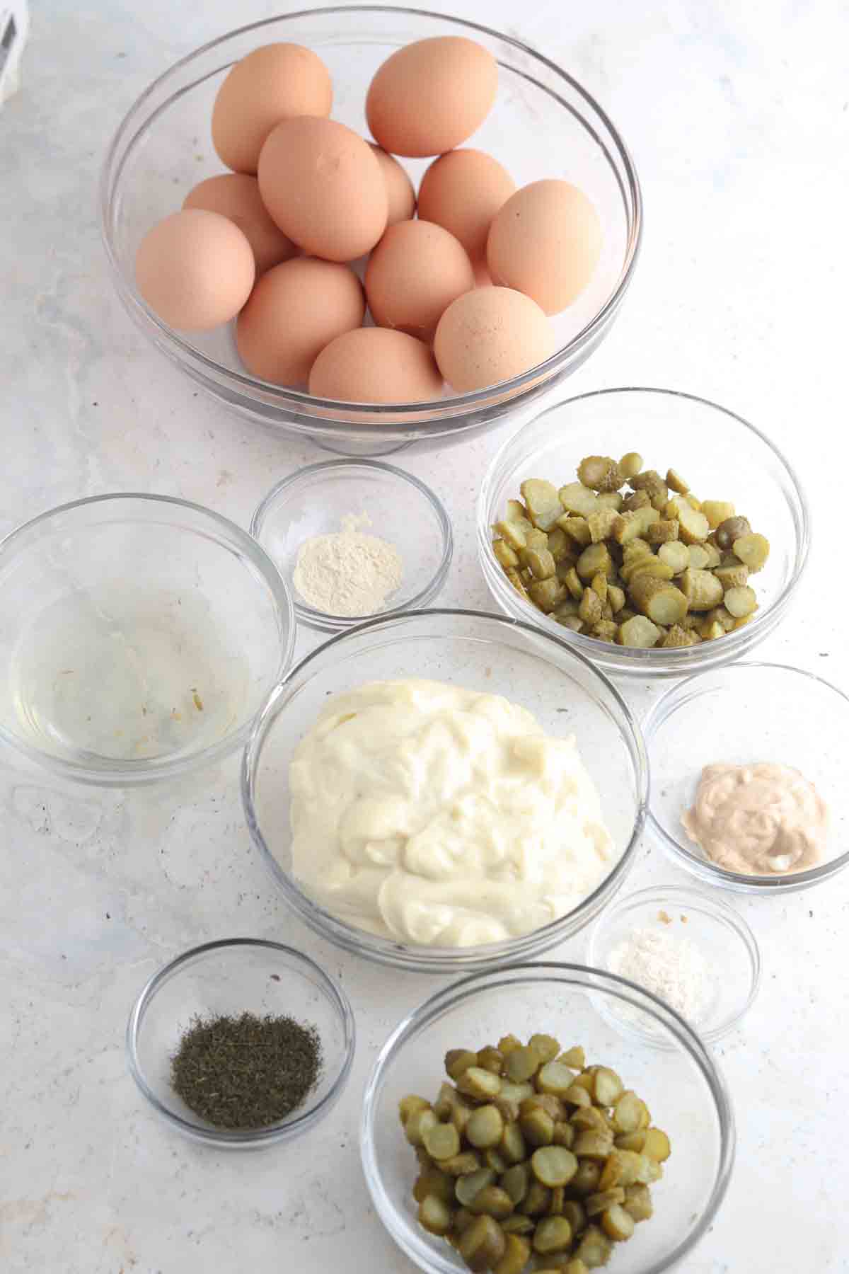 Egg salad ingredients laid out in small glass bowls.