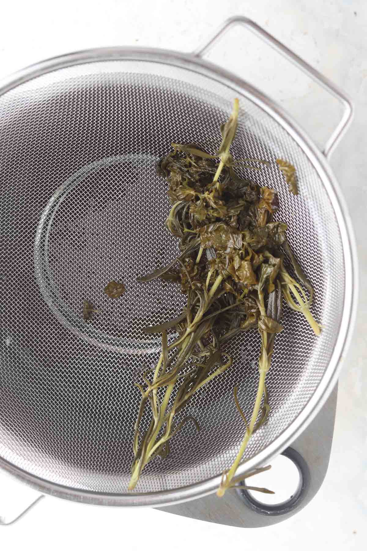 Strained rosemary and mint in a sauce pot.