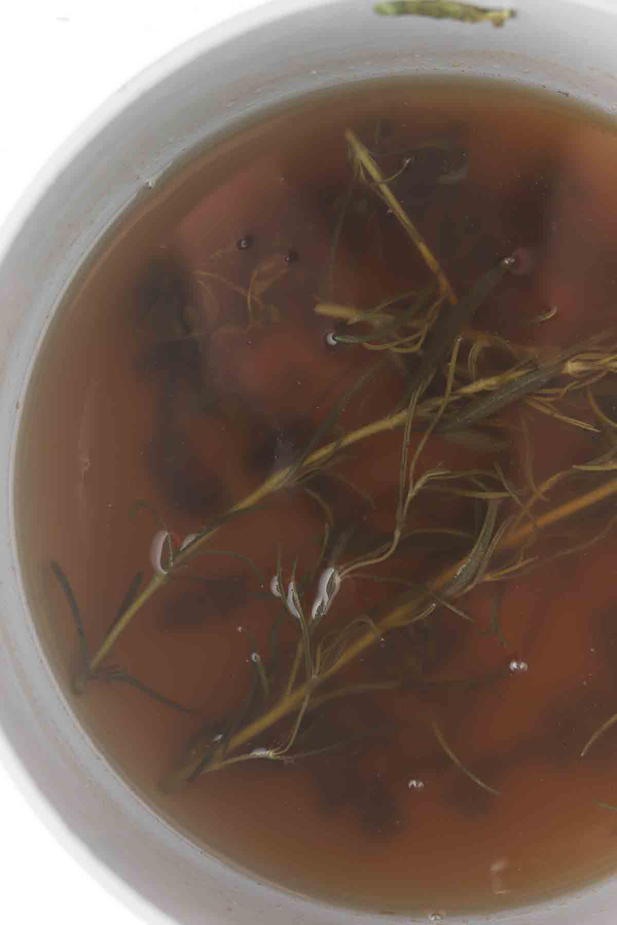 Water, honey, rosemary, and mint in a sauce pot.