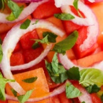 Close up photo of cantaloupe, watermelon, mint and onions.