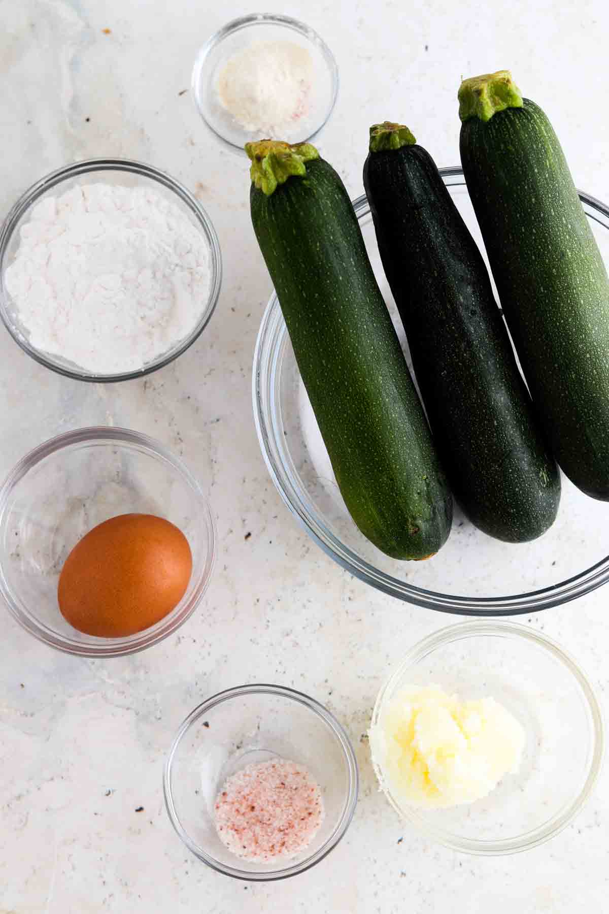 Zucchini, egg, salt, tallow, garlic powder and onion powder in small glass bowls. 