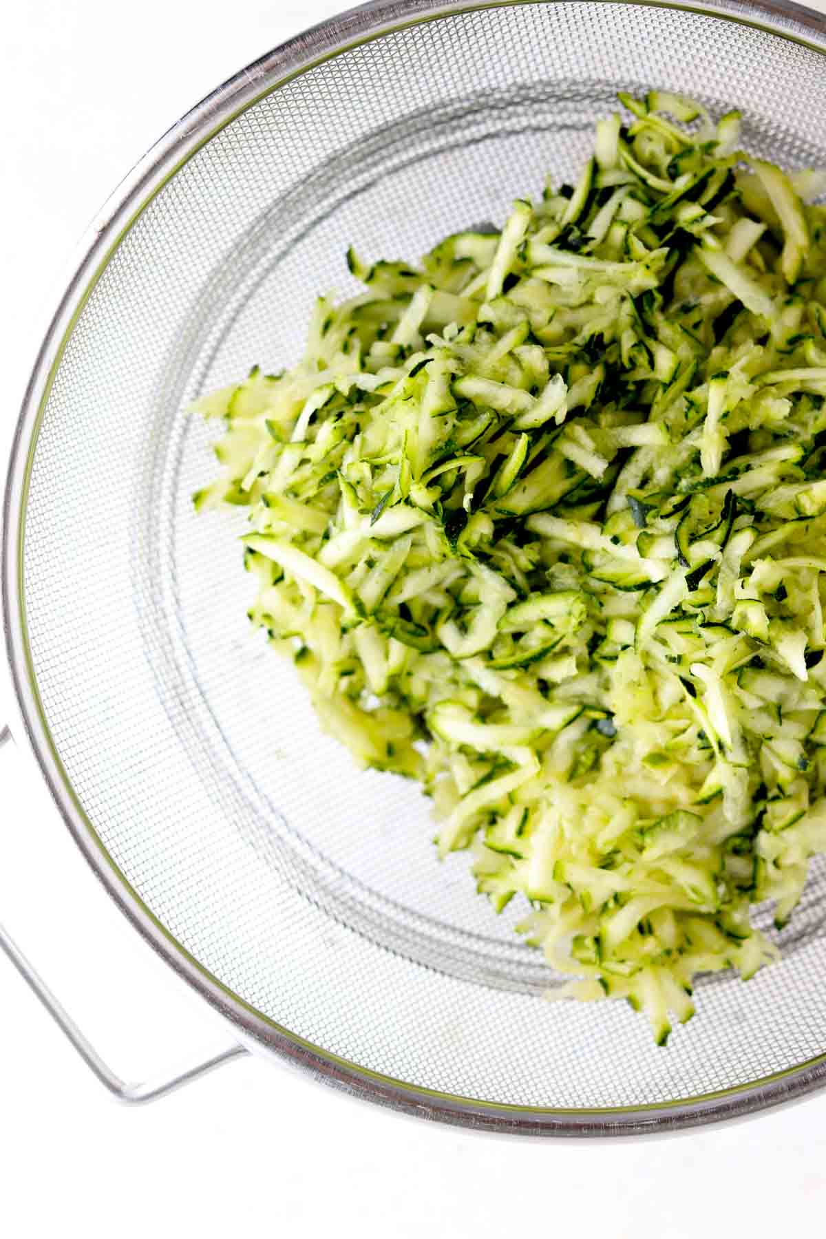 Zucchini strained over a bowl. 